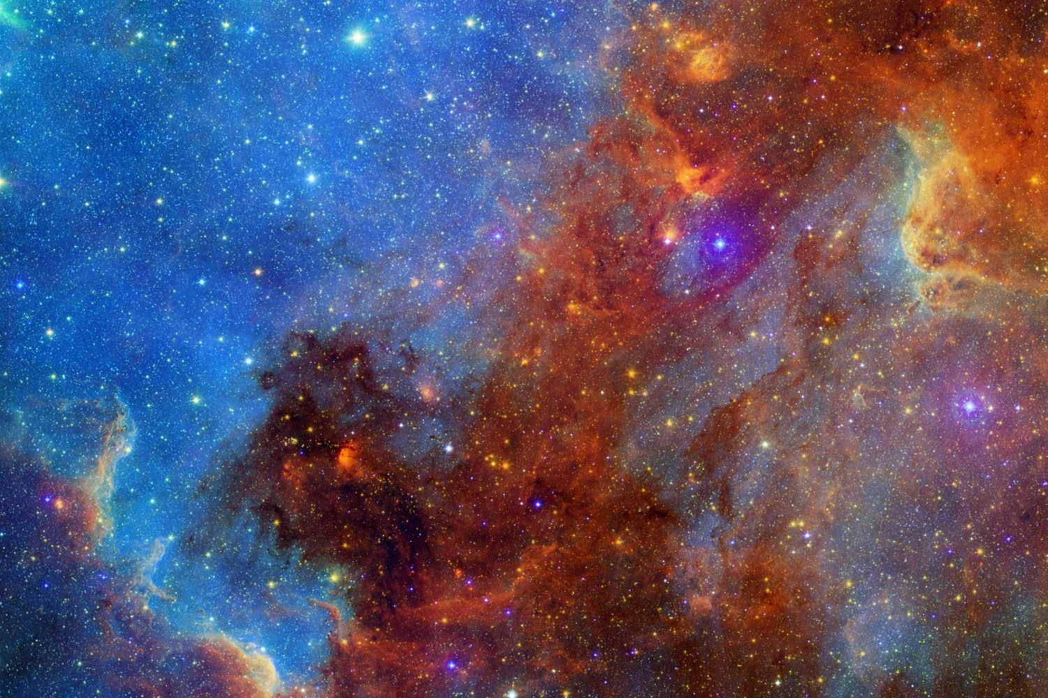 A nebula of blue, orange and red clouds crowded with stars, in false colour.
